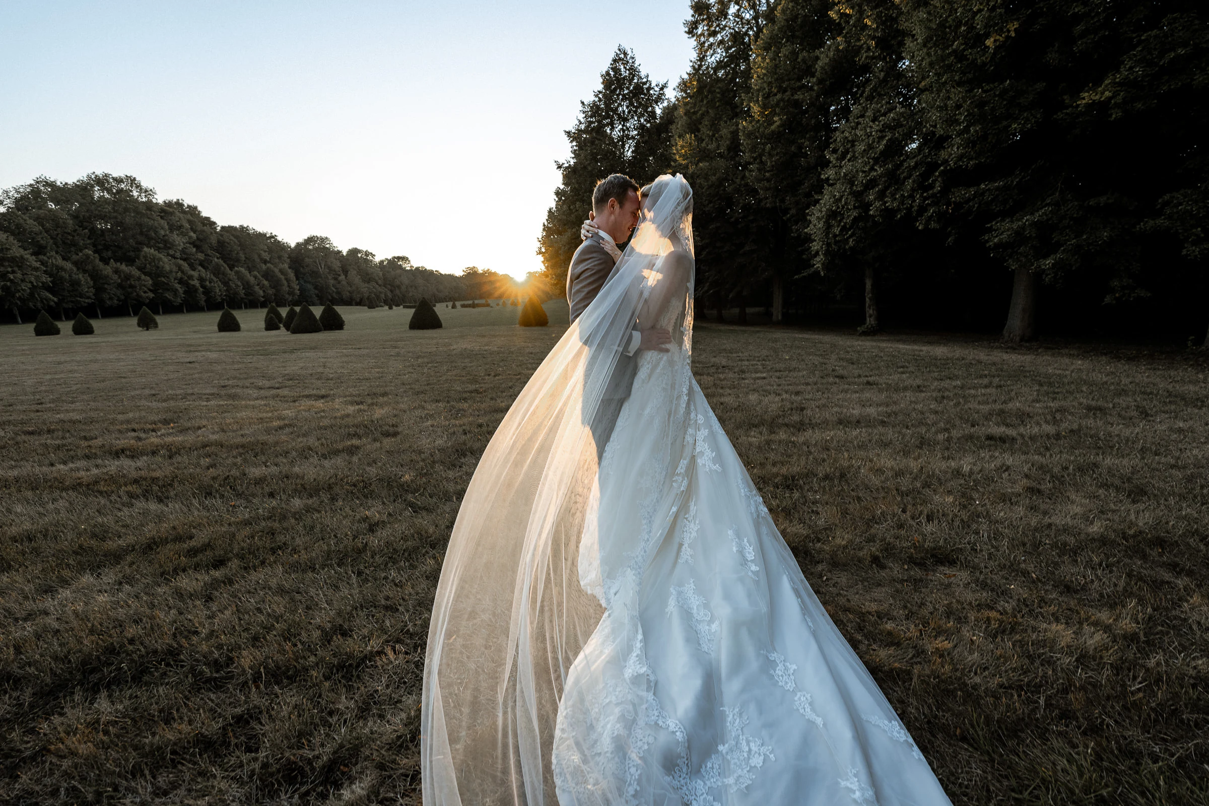 A kiss at sunset in the park, veil spread over the grass, château de Champlâtreux