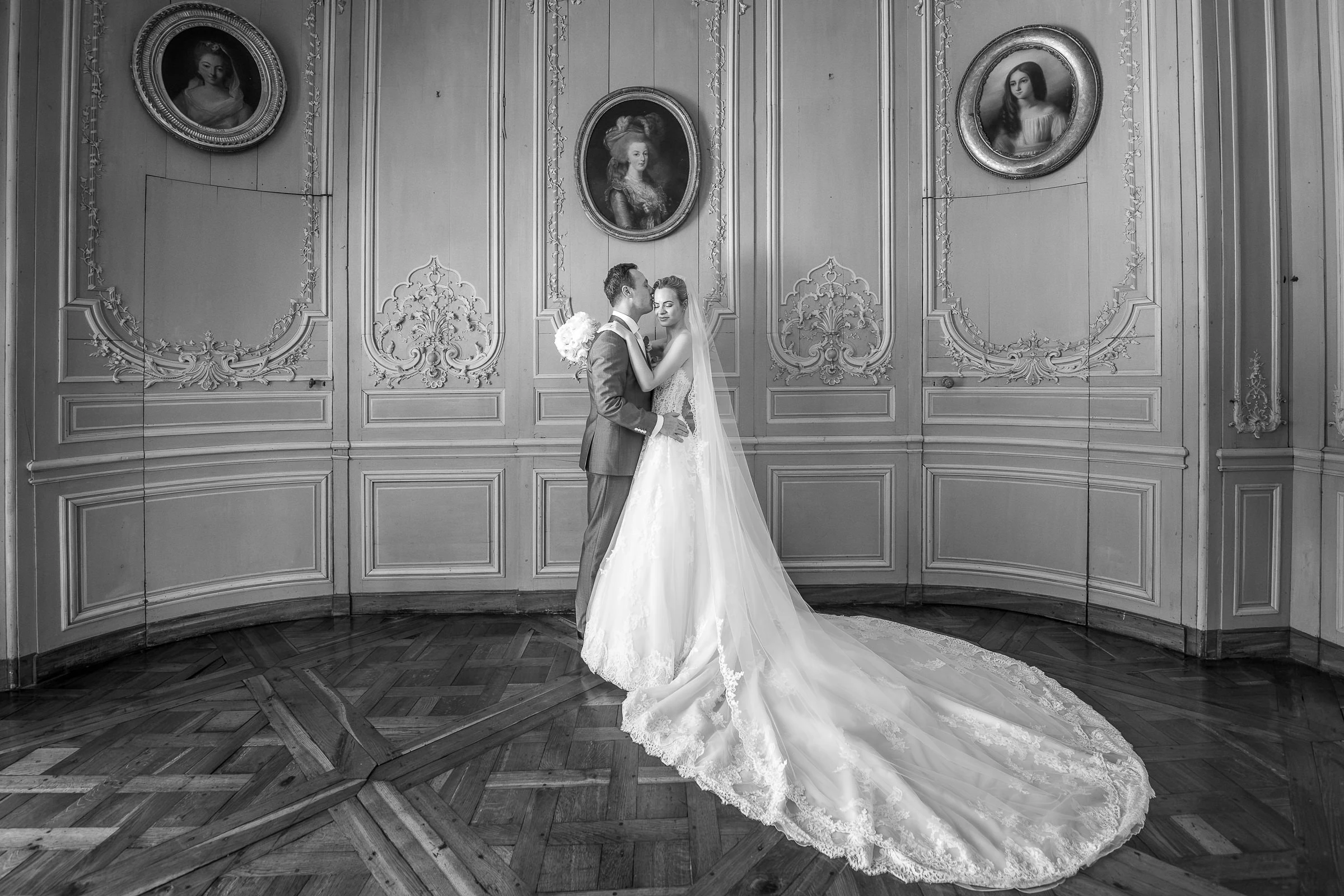 Baiser des mariés dans le salon aux boiseries et portraits anciens, noir et blanc, château de Champlâtreux