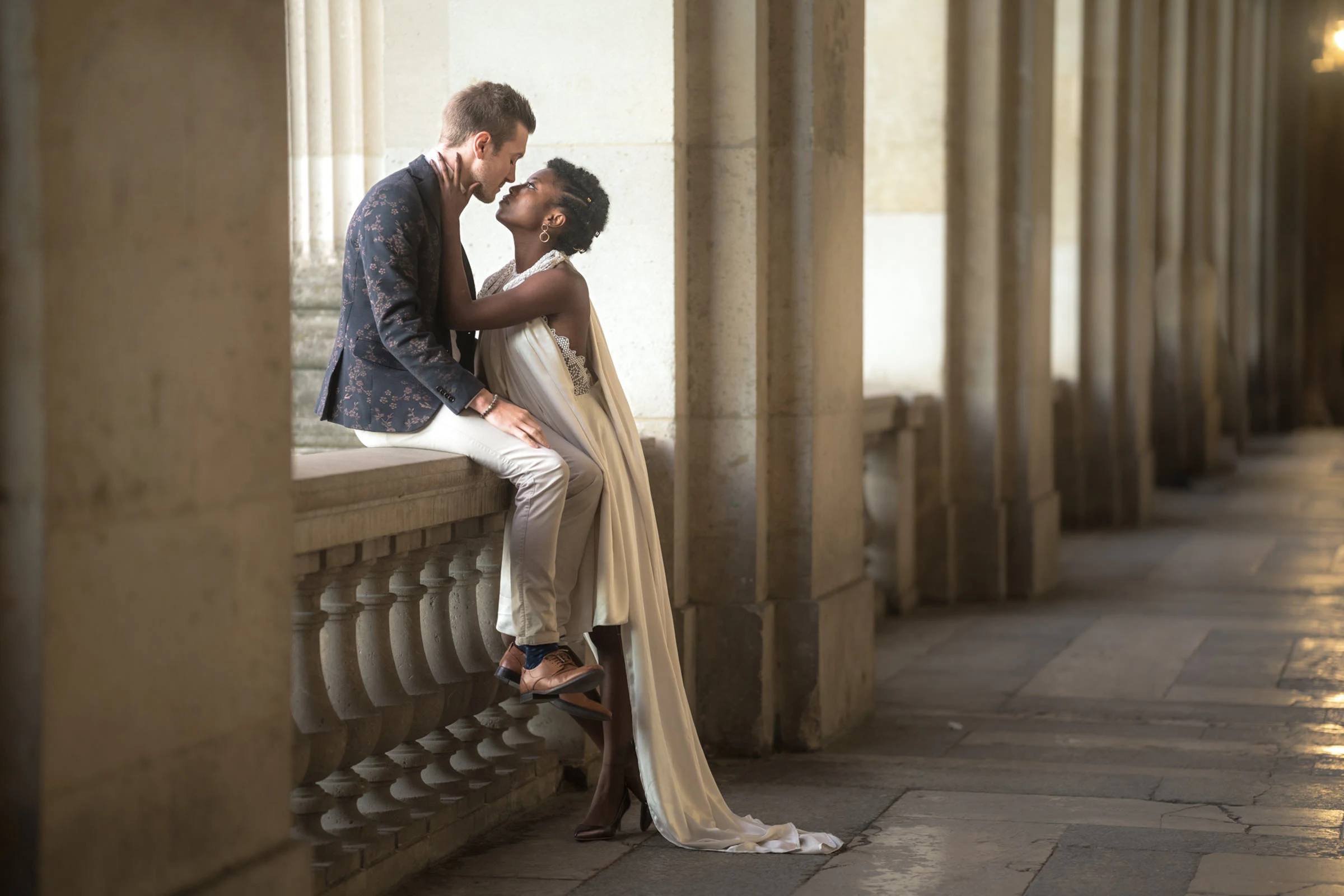 The couple beneath the arcades of the Louvre, golden light, Paris
