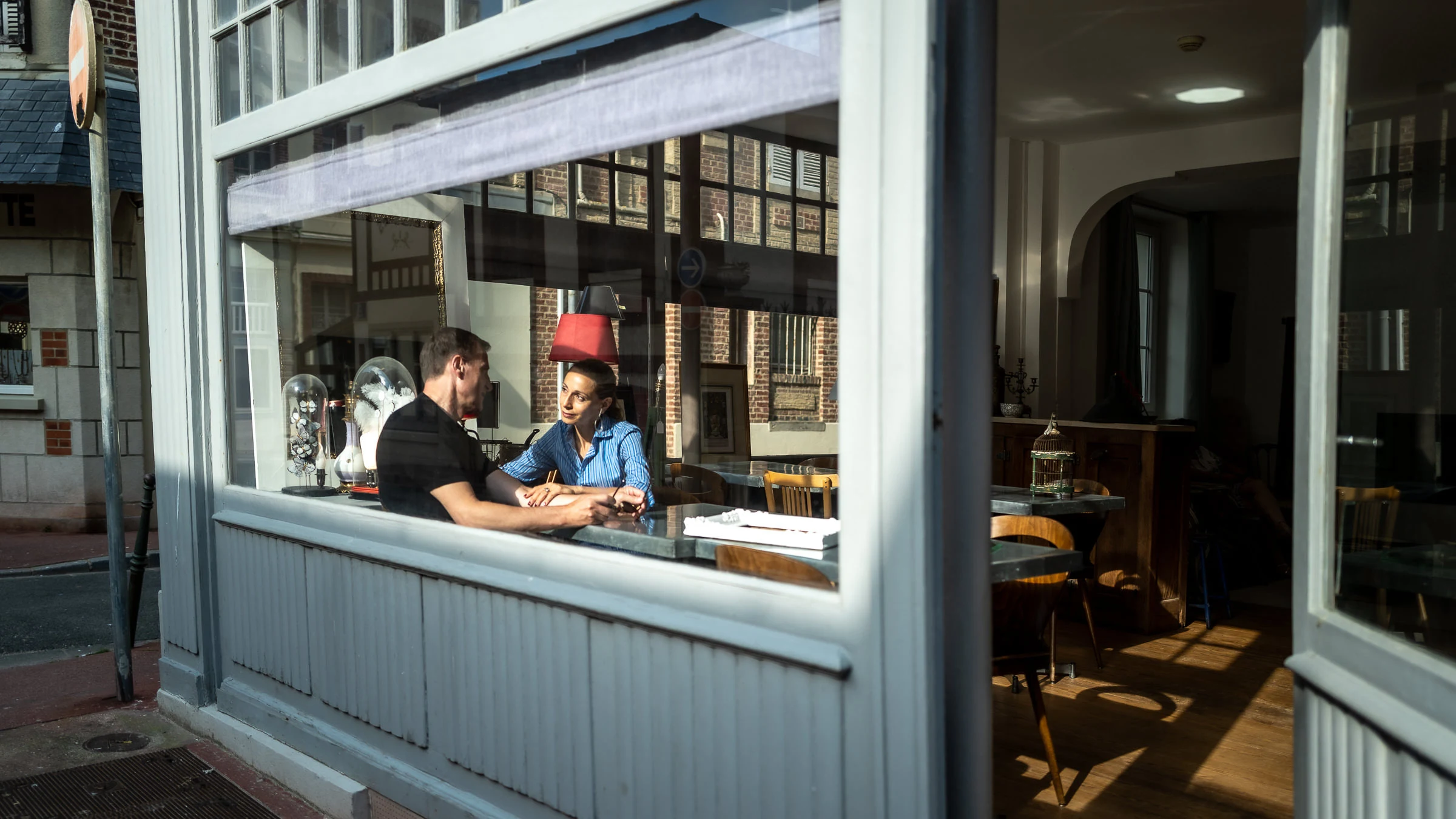 Le couple attablé derrière la vitrine d’un café de Trouville