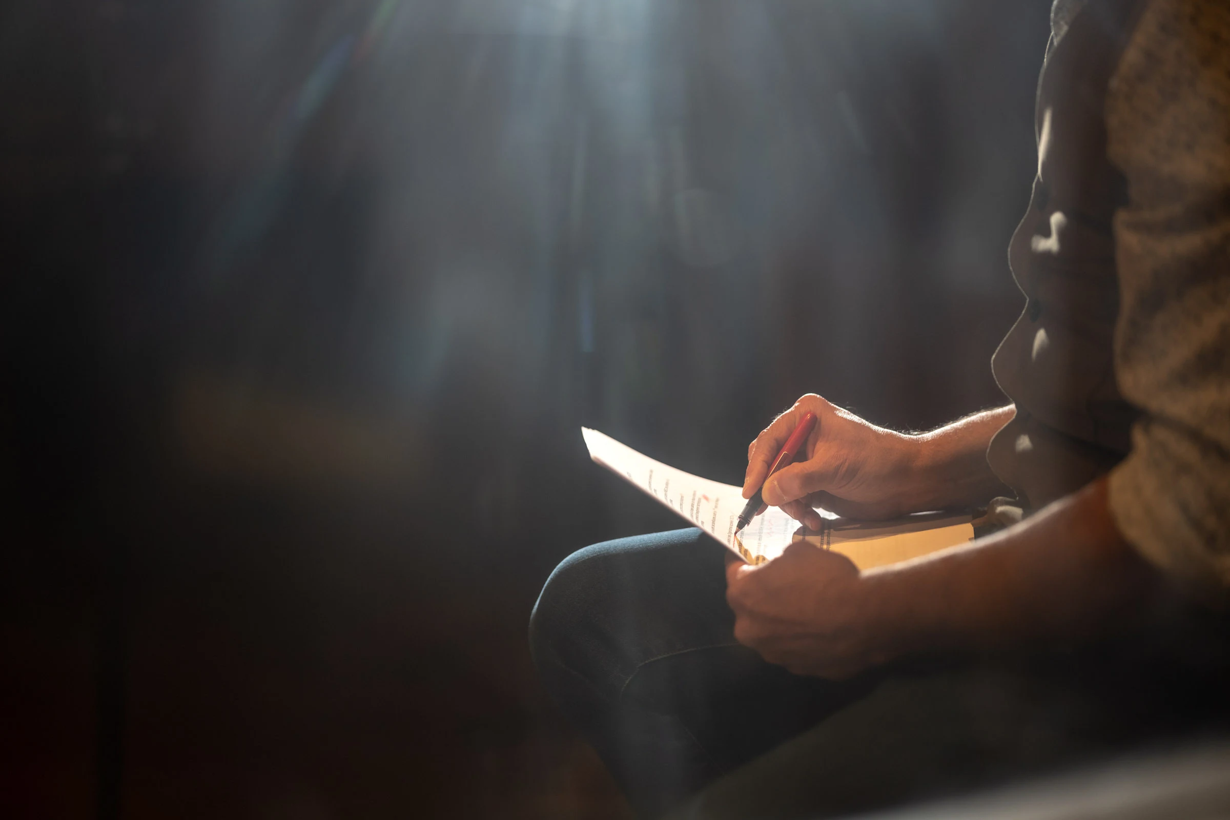 A hand writing in a shaft of light