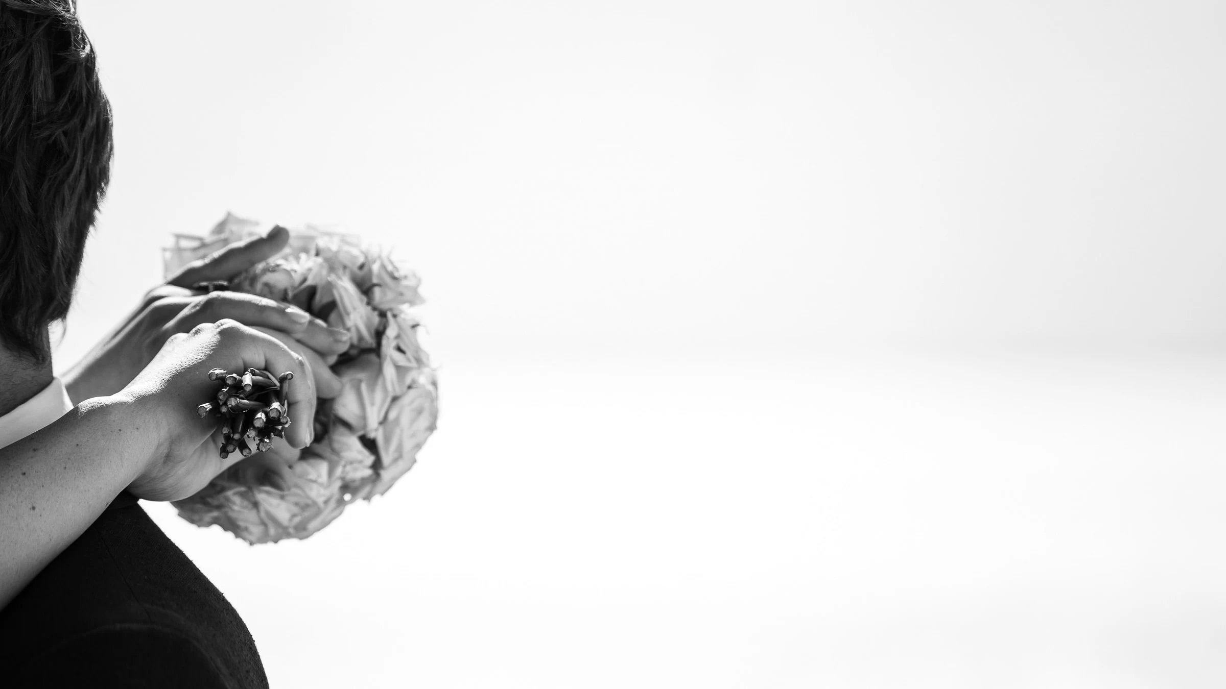 The couple’s hands on the bouquet, high-key black and white, Royan