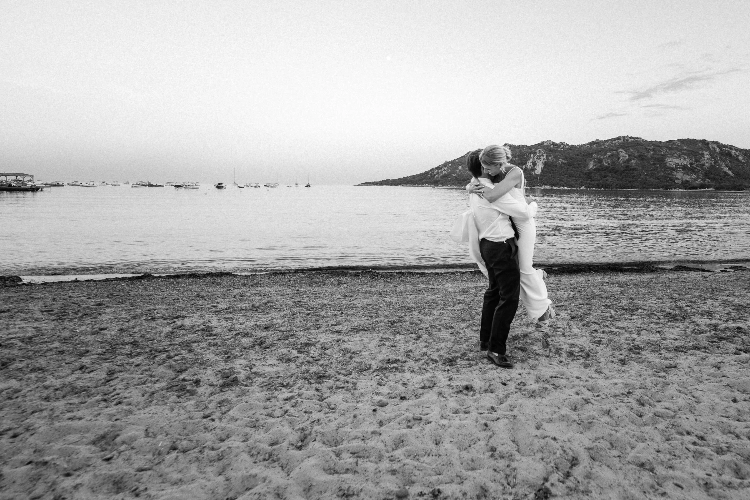 The groom carries the bride along Santa Giulia beach, black and white, Porto-Vecchio, Corsica