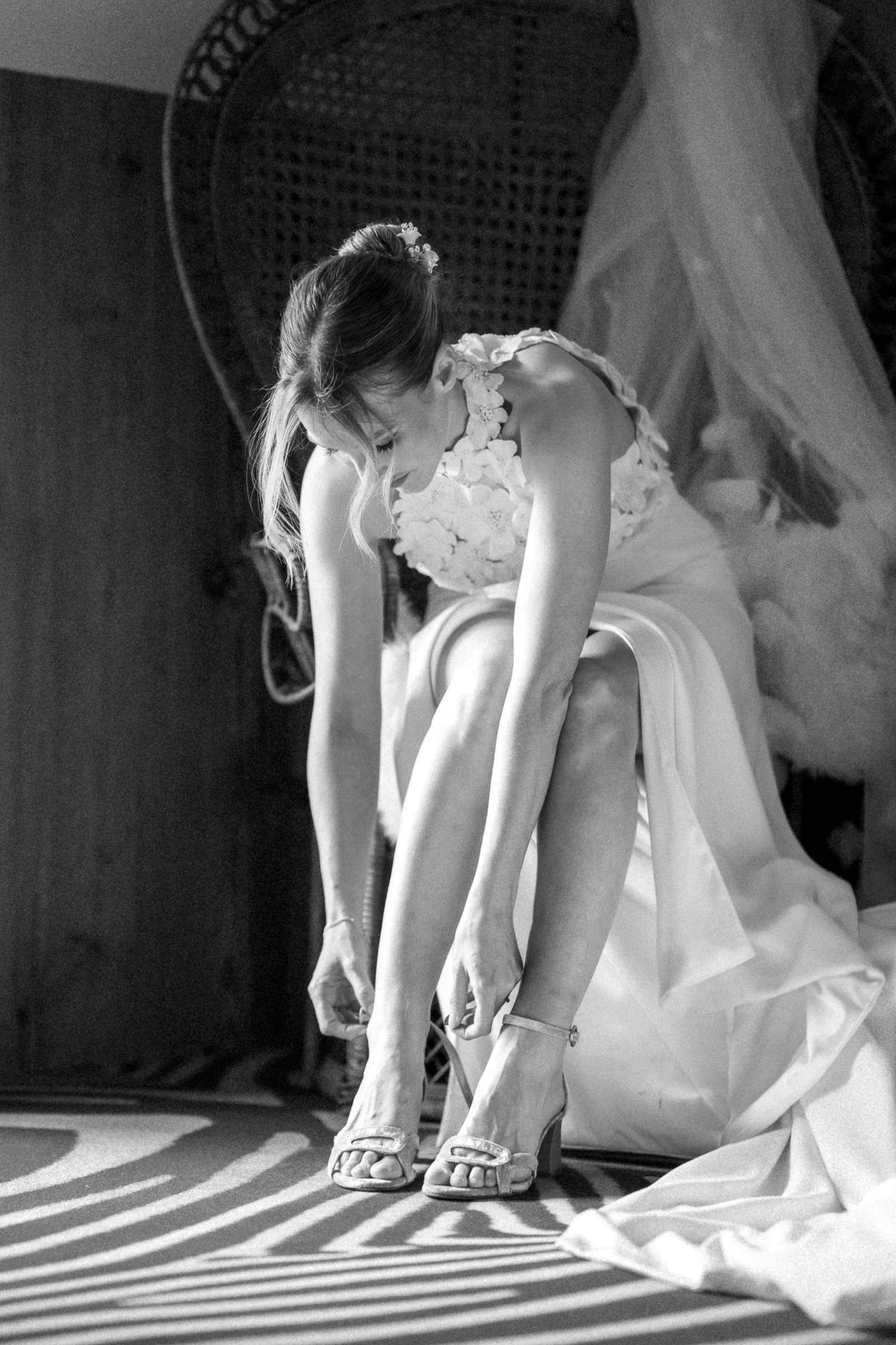 The bride fastening her shoes in striped light, black and white, a wedding in the Loiret