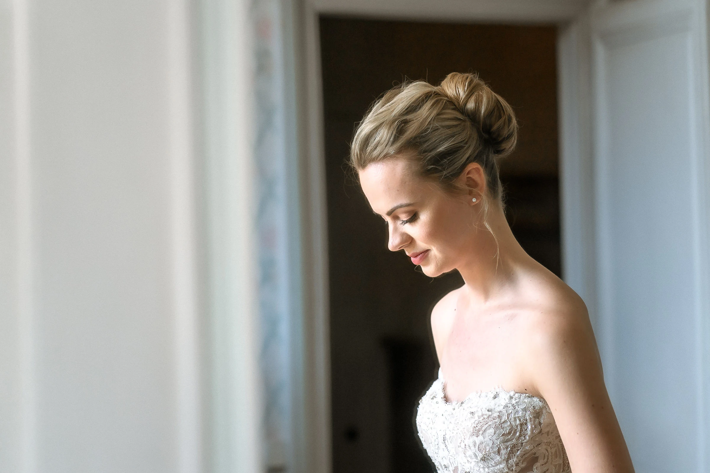 La mariée de profil, chignon haut, dans l’encadrement d’une porte, château de Champlâtreux
