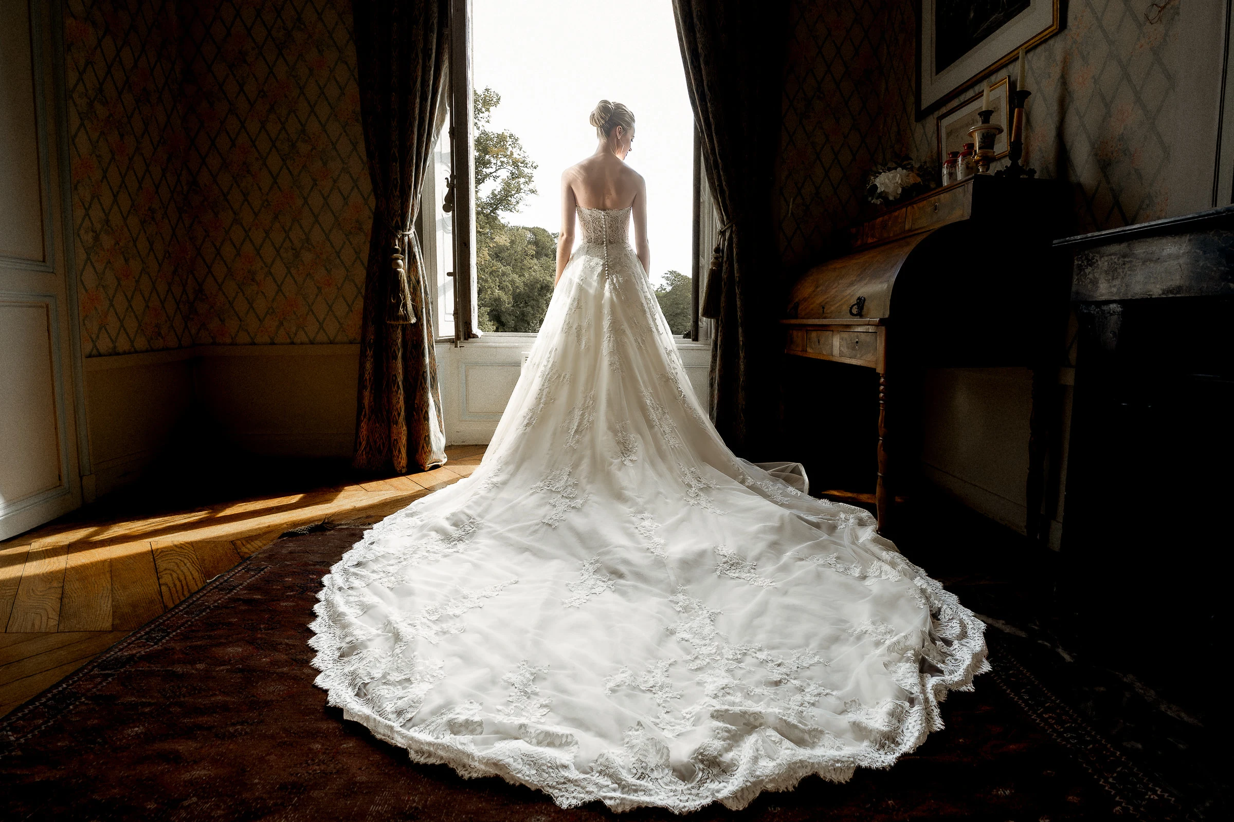 La mariée à la fenêtre, traîne déployée dans le salon du château de Champlâtreux