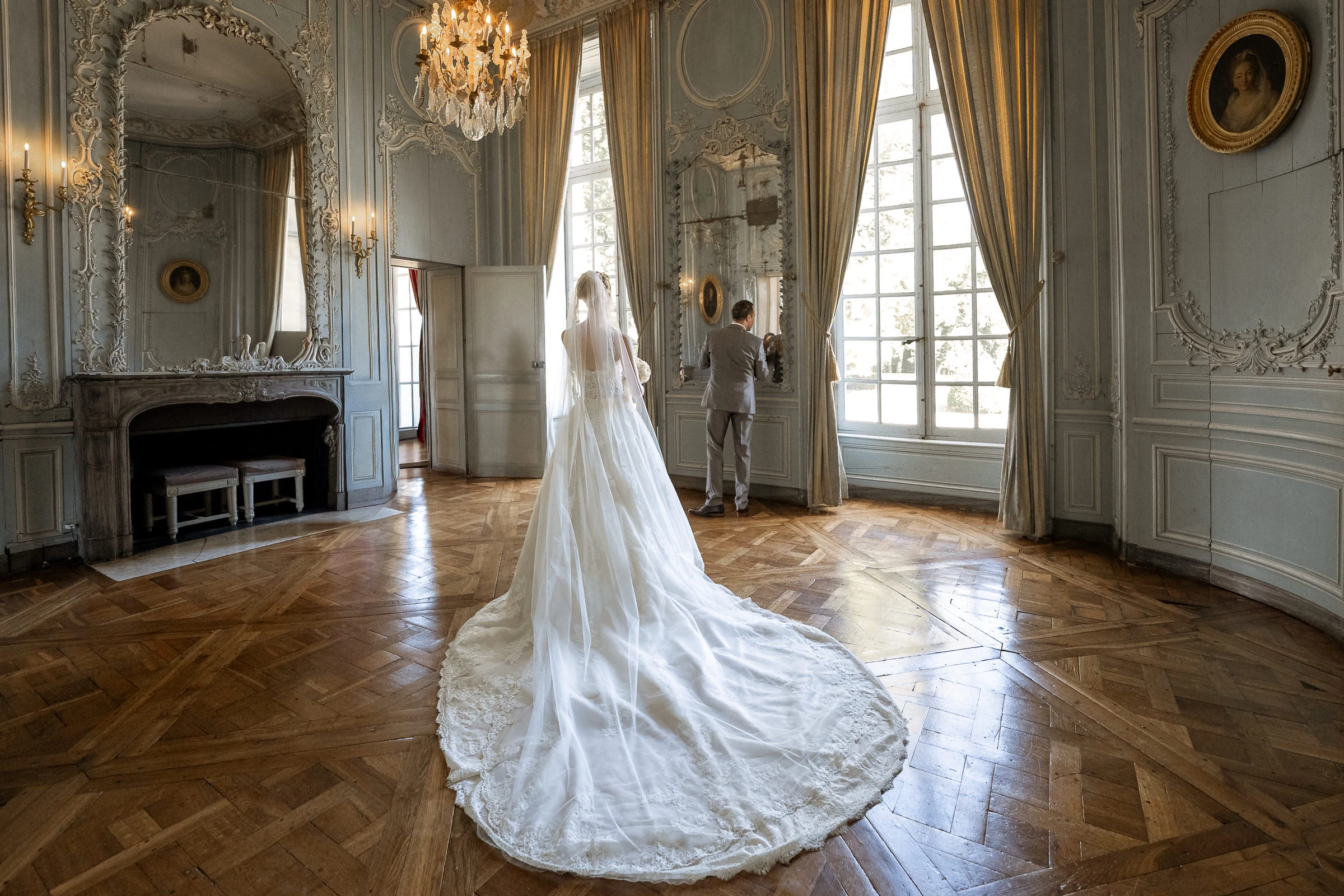 La mariée et sa traîne dans le grand salon, le marié à la fenêtre, château de Champlâtreux