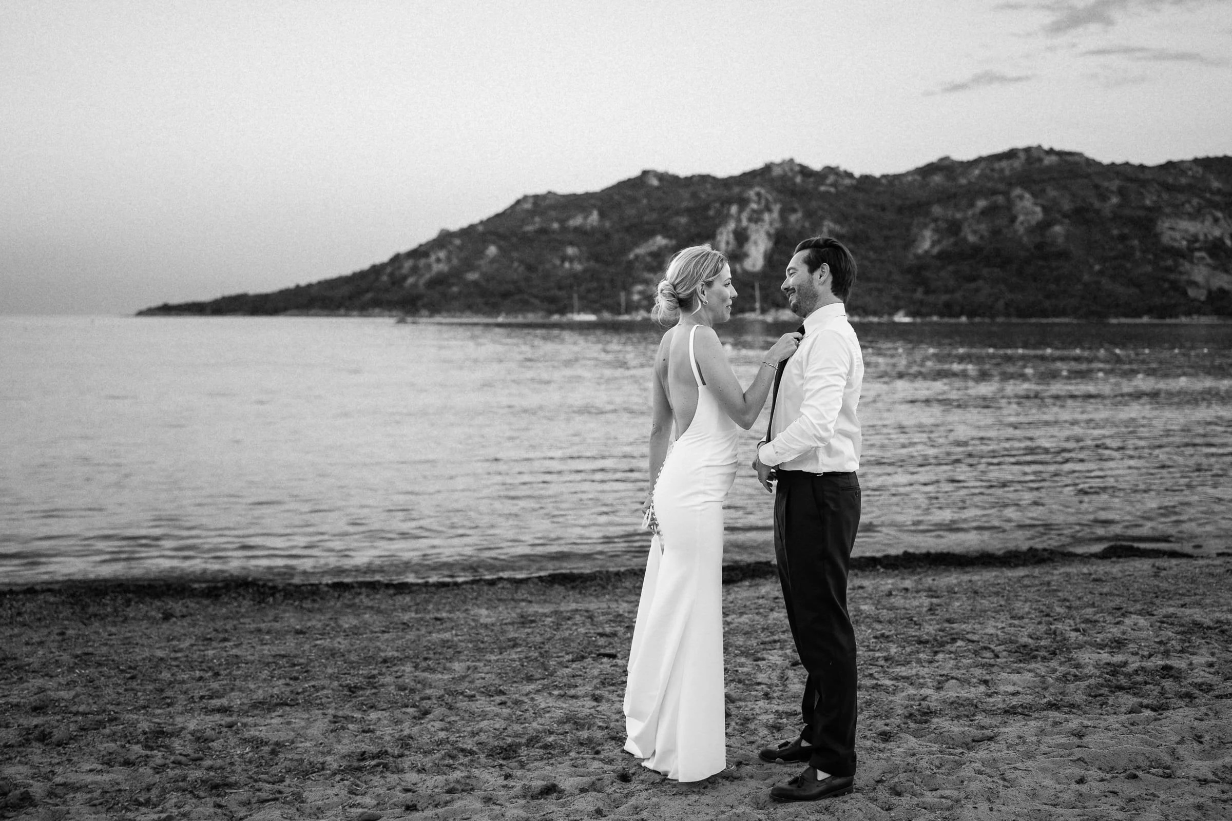 Les mariés face à face sur la plage, montagnes en fond