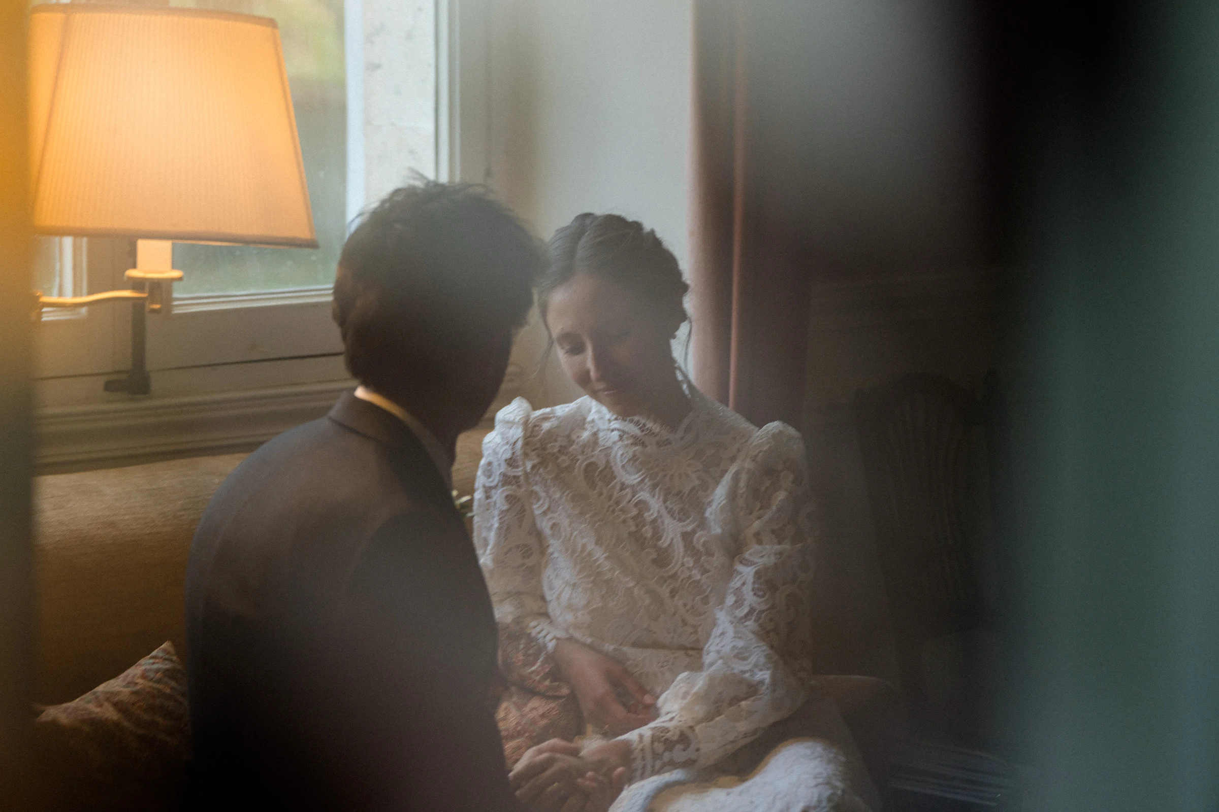 The couple in the warm light of a lamp, a high-necked lace gown