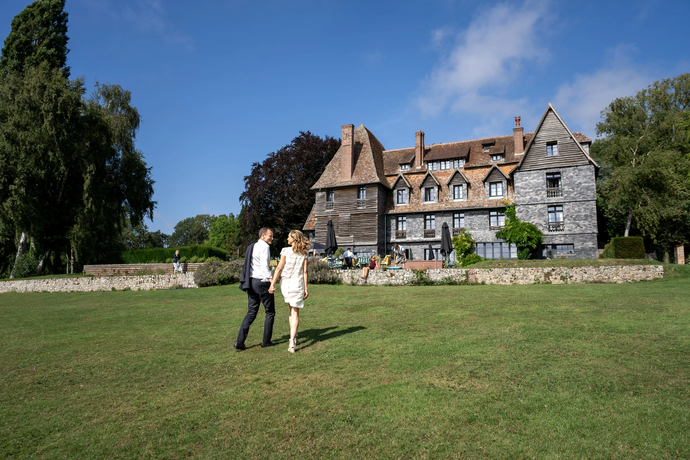 Les mariés traversent le parc du manoir, jardins de Coppélia