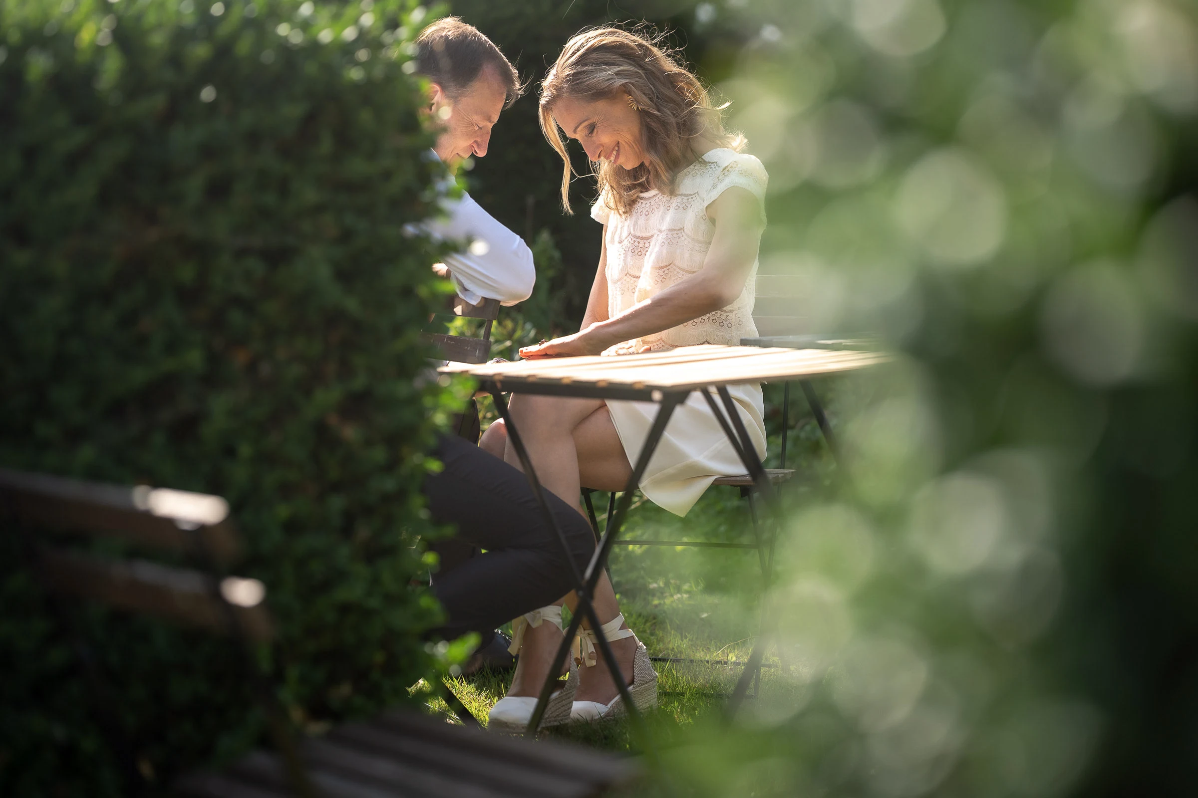 Les mariés attablés au jardin, vus à travers la végétation
