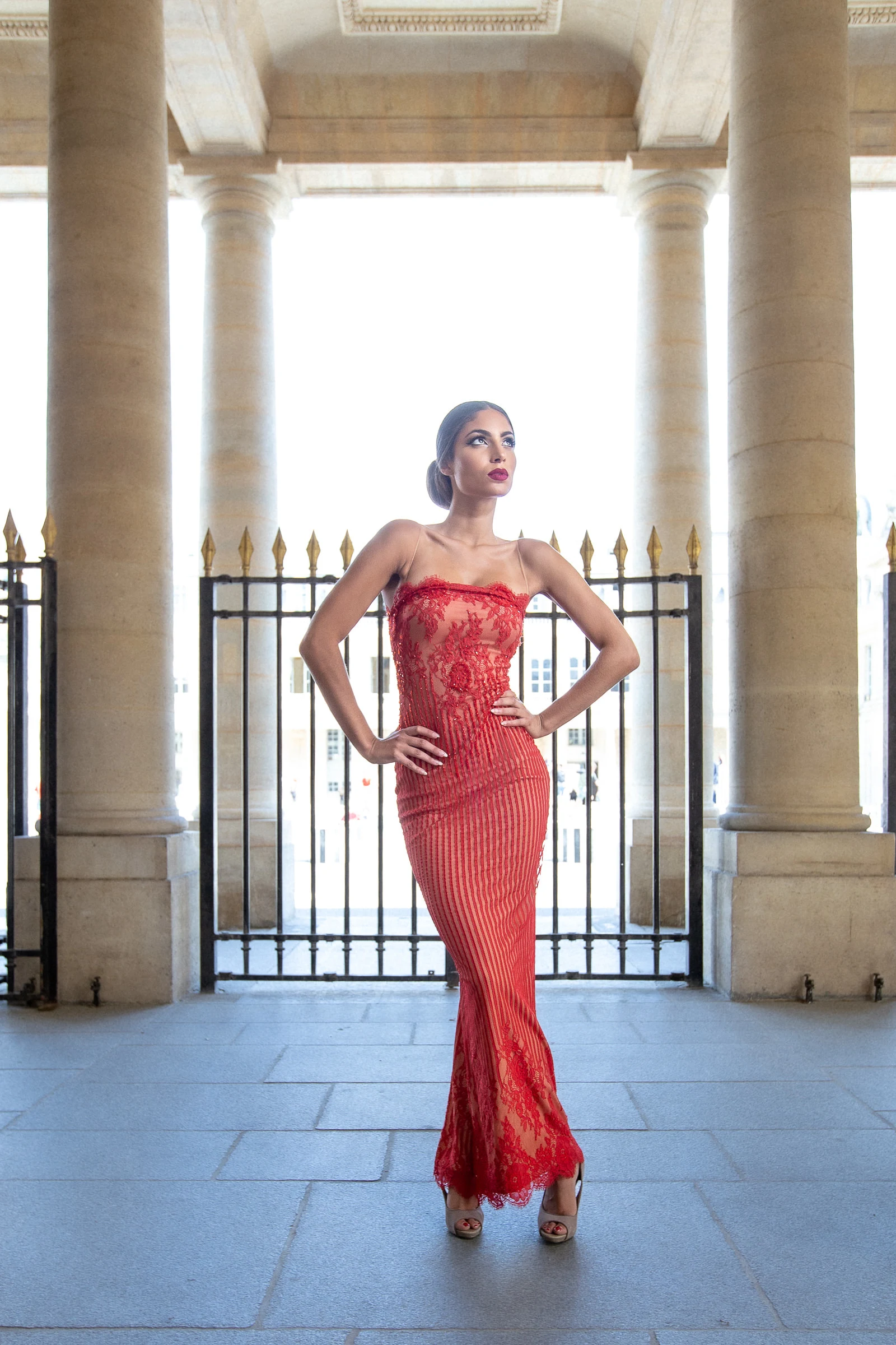 Robe rouge de dentelle devant les grilles dorées du Palais-Royal, Paris
