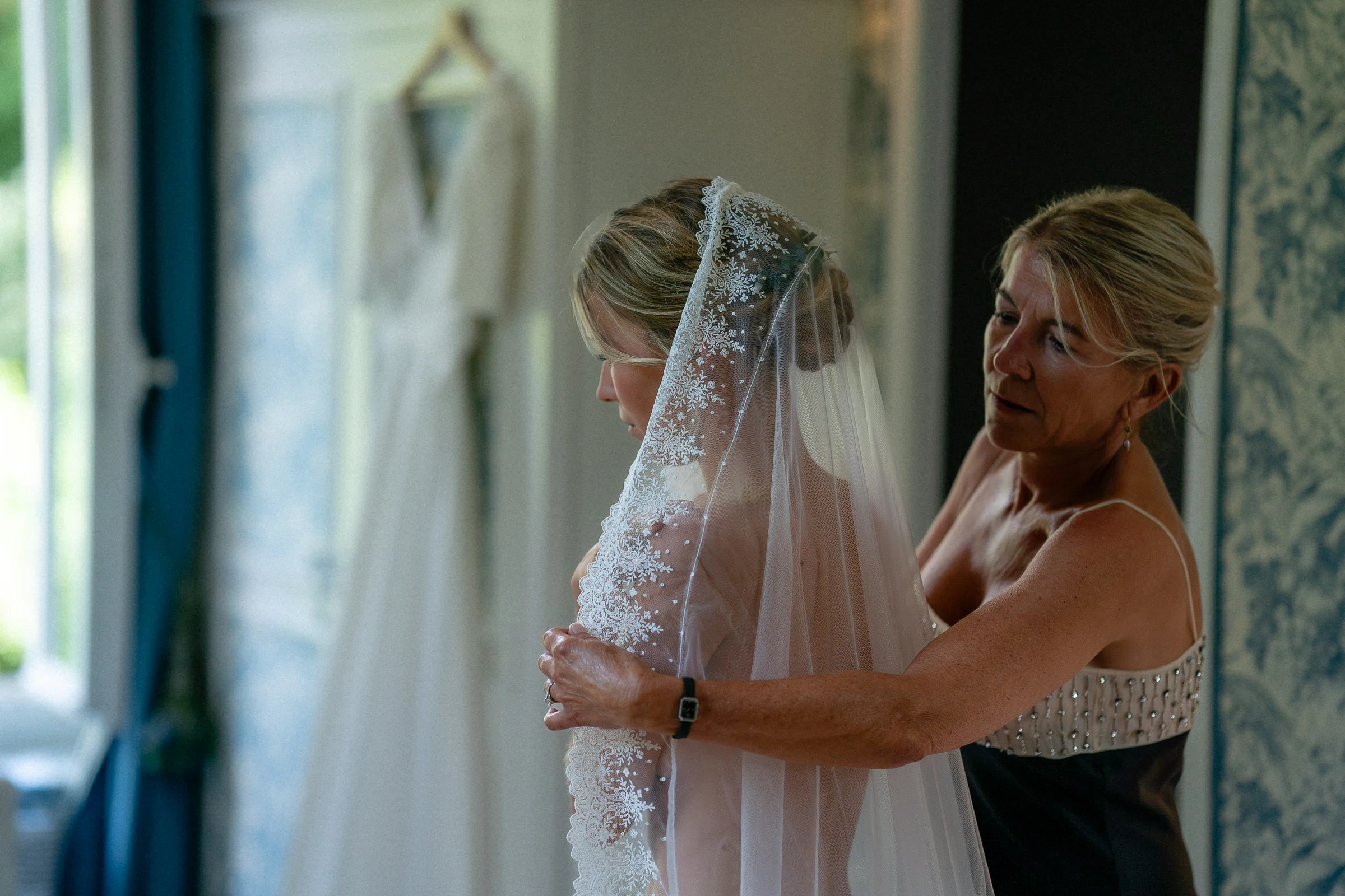 Her mother adjusts the bride’s veil during the preparations, château du Pont-Chevron, Ouzouer-sur-Trézée