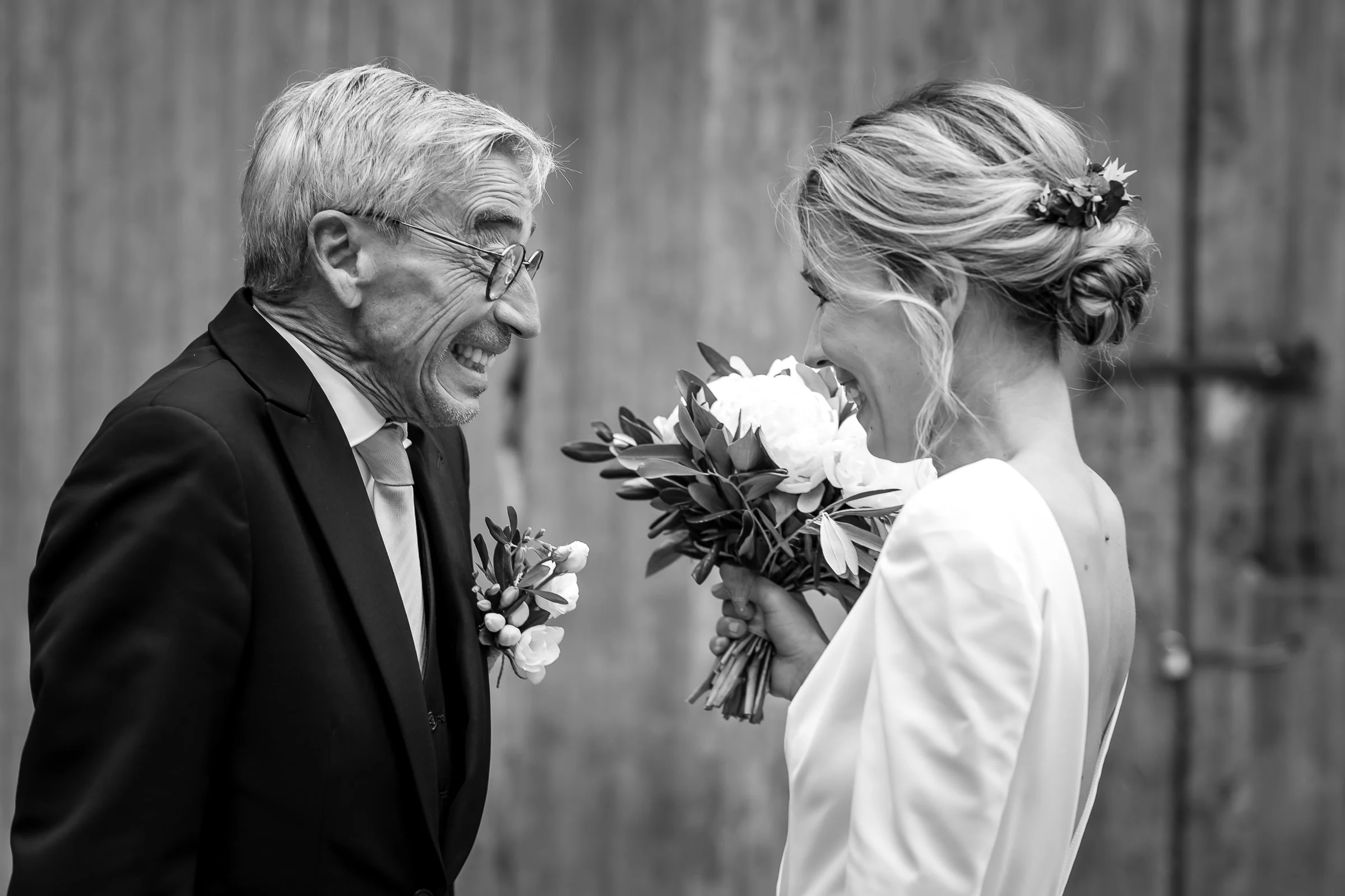 The father laughing before the bride and her bouquet, black and white, château du Pont-Chevron