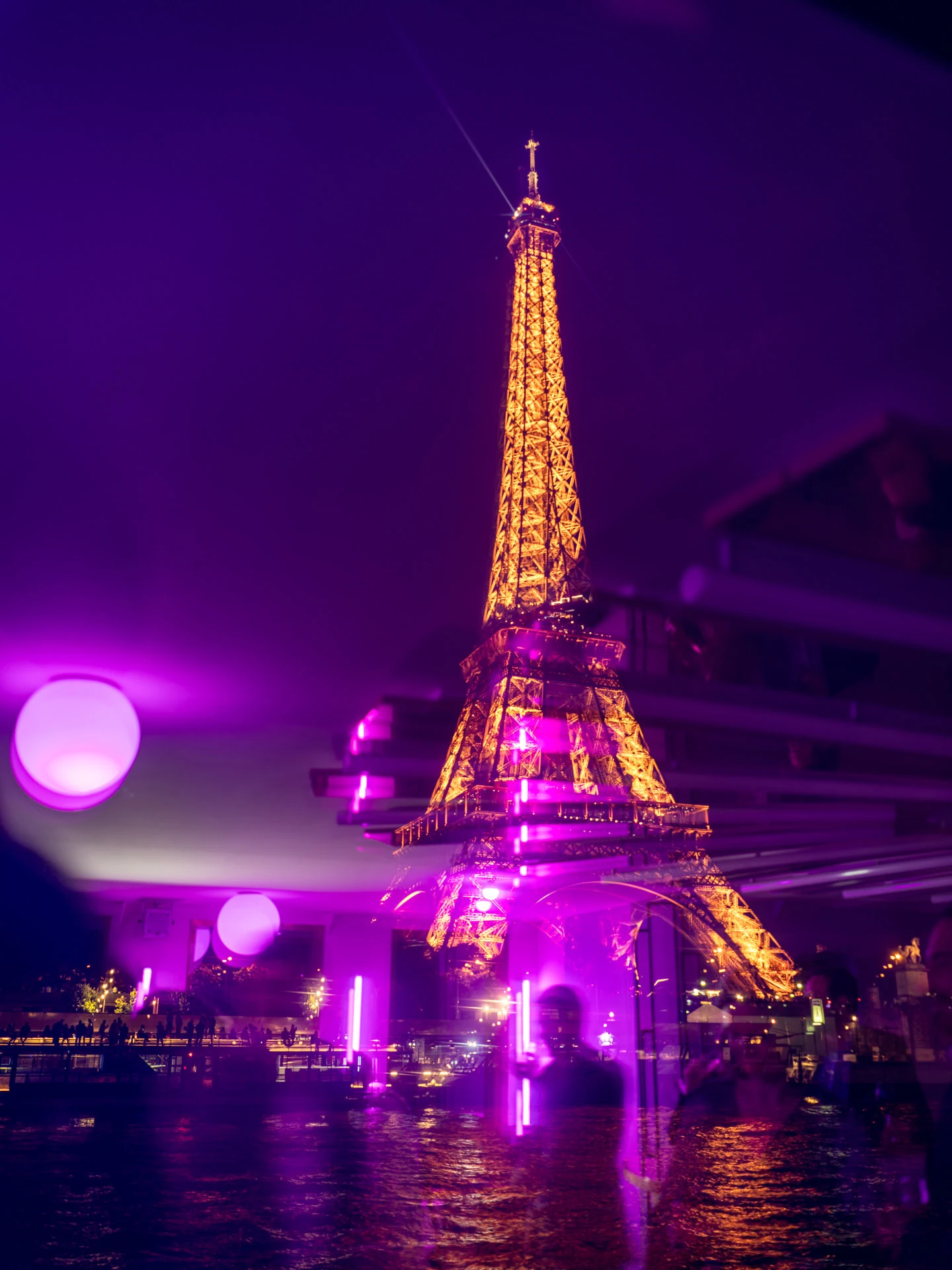 La tour Eiffel de nuit et ses reflets violets sur la Seine