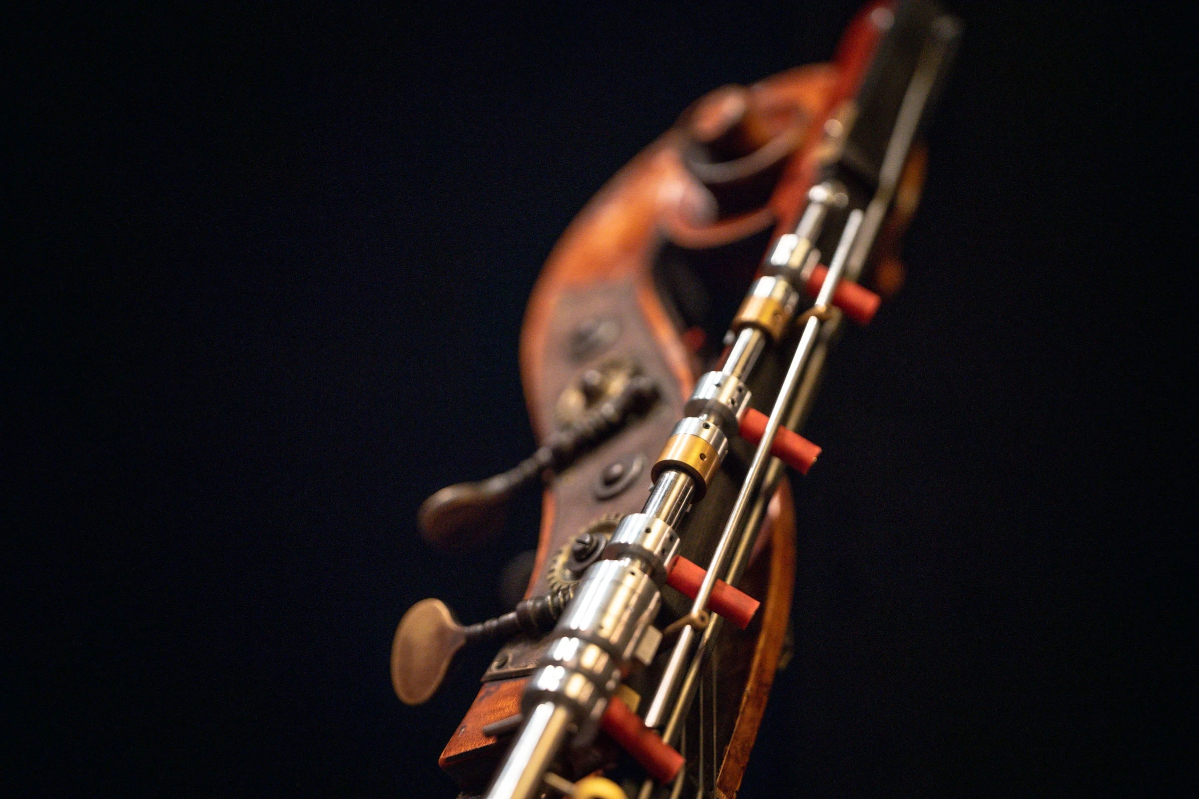 The scroll of a double bass against a black ground